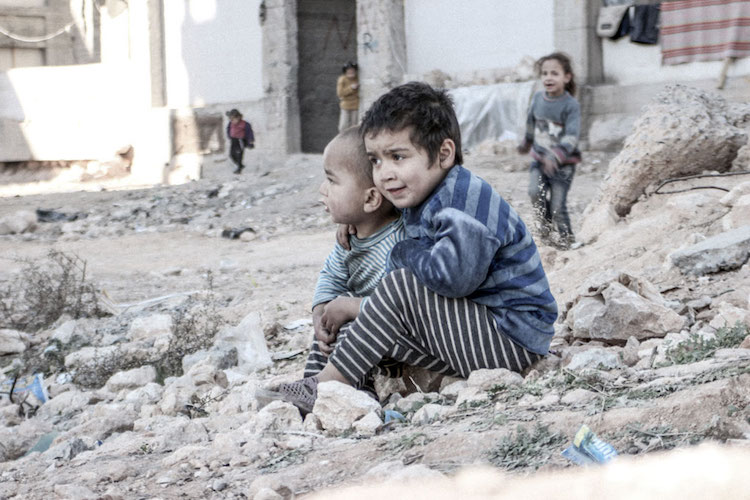 Photo: In Aleppo, Syria, four-year-old Esraa and her brother Waleed, three, sit on the ground near a shelter for internally displaced persons. Credit: UNICEF/UN013175/Al-Issa